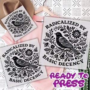 May include: Three white heat transfer vinyl sheets with a black bird and floral design, and the text "RADICALIZED BY BASIC DECENCY". A pink t-shirt and a hat are in the background. The text "READY TO PRESS" is also visible.