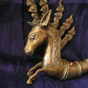 May include: A bronze sculpture of a mythical creature with a horse-like body and a head with multiple human figures on its back. The sculpture is detailed with intricate carvings and has a dark brown patina.