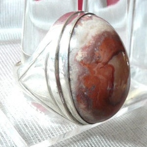 Pu&ograve; includere: Un anello d'argento con una grande pietra di agata ovale di colore rosso e bianco.