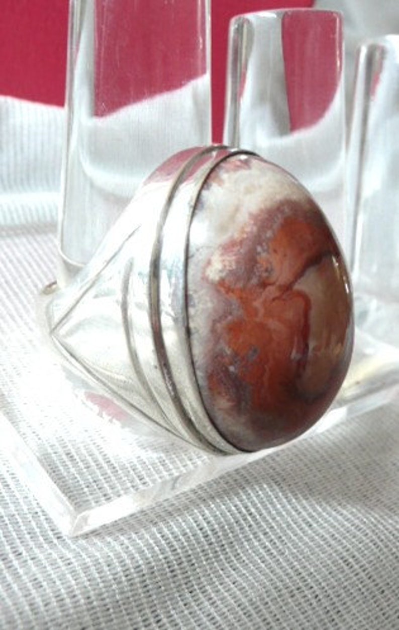 Pu&ograve; includere: Un anello d'argento con una grande pietra di agata ovale di colore rosso e bianco.