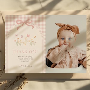 May include: A rectangular thank you card featuring a light pink gingham pattern on the left side with an arched frame, a bow, a duck illustration, and the text: THANK YOU for making my first birthday so magical! LOVE, EMMA. A photo of a baby is on the right.