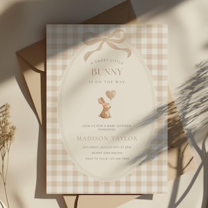 May include: A baby shower invitation with a beige gingham pattern background. The invitation features the text "A SWEET LITTLE BUNNY IS ON THE WAY" and a watercolor illustration of a bunny holding a heart-shaped balloon. Details include the honoree's name, date, time, and RSVP information.