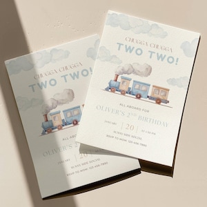 Könnte beinhalten: Zwei hellblaue Geburtstagseinladungen mit einer Aquarell-Zug-Illustration. Der Text "CHUGGA CHUGGA TWO TWO!" steht oben, mit Details für Olivers 2. Geburtstag darunter. Die Einladungen liegen auf einer hellbeigen Oberfläche.