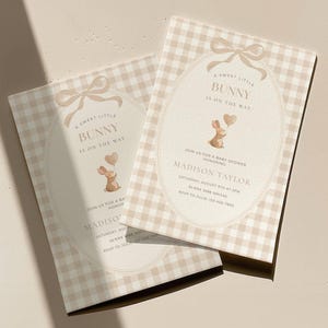 May include: Two baby shower invitations with a bunny theme. The invitations feature a beige gingham pattern and an oval design with a bow and the text "A Sweet Little Bunny Is On The Way." The invitations include the name "Madison Taylor."