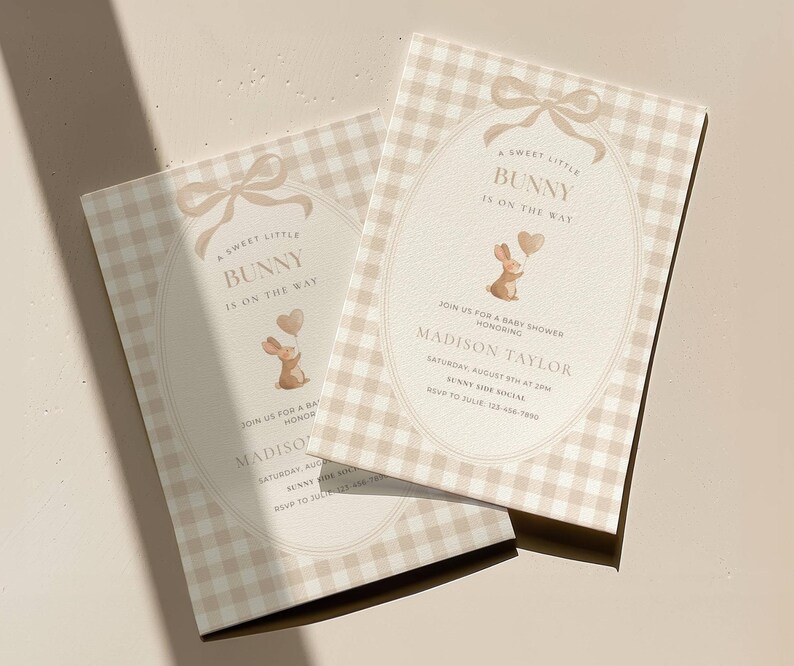 May include: Two baby shower invitations with a bunny theme. The invitations feature a beige gingham pattern and an oval design with a bow and the text "A Sweet Little Bunny Is On The Way." The invitations include the name "Madison Taylor."