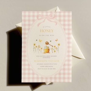May include: A baby shower invitation with a pink gingham background. The invitation features an oval design with a bow, the text "A Little Honey Is On The Way", and a watercolor illustration of a honey pot, flowers, and bees.