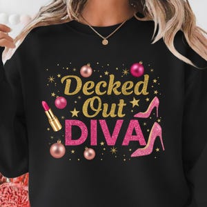 May include: Black sweatshirt with the text "Decked Out DIVA" in gold glitter and pink glitter. The design includes pink ornaments, stars, a lipstick, and pink high heels.