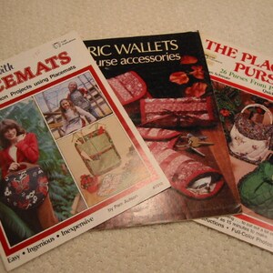 May include: Three vintage sewing pattern books. The titles include "Crafty Ideas with Placemats", "Fabric Wallets Purse Accessories", and "The Placemat Purse". The covers feature images of purses and wallets.