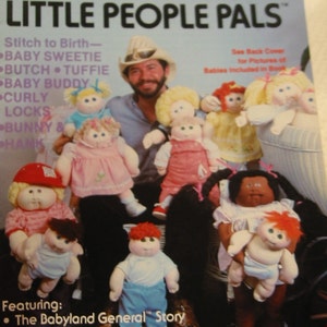 May include: A vintage book cover titled "LITTLE PEOPLE PALS" featuring a man and several dolls. The dolls have various hairstyles and outfits. The cover includes text such as "Stitch to Birth" and "Xavier Roberts' Life & Works."