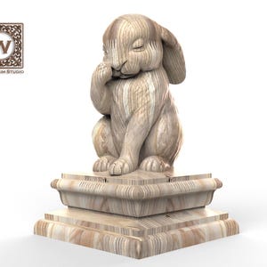 May include: A light brown wooden sculpture of a rabbit sitting on a two-tiered square base. The rabbit has one paw raised to its face and closed eyes. The Wood Trim Studio logo with a letter W is visible in the top left corner of the image.