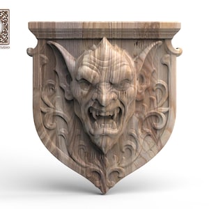 Puede incluir: Una placa de pared de madera marrón claro con una talla en relieve detallada de una cara de gárgola gruñendo con orejas puntiagudas y colmillos visibles. La criatura está centrada en una base en forma de escudo con volutas.