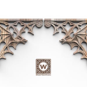 May include: Two symmetrical wooden corbels featuring intricate carvings of bats with spread wings integrated into a pointed arch design. The natural wood grain is visible throughout the structure. A square logo with the letter W and the text Wood Trim Studio is centered below the two pieces.