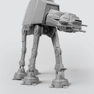 May include: A gray AT-AT model, a four-legged combat vehicle from the Star Wars franchise. The model is detailed with panels, joints, and weaponry, standing on a light gray surface. The vehicle's design is reminiscent of a mechanical walker.