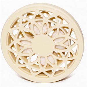 May include: A cream-coloured, circular decorative object with a geometric openwork design. The centre features a solid circle, and the openwork reveals a glimpse of the interior. The object appears to be made of a solid material.