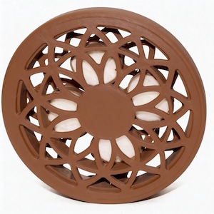 May include: A brown, circular decorative object with a floral, openwork design. The center features a solid brown circle, and the openwork reveals a white interior. The object is likely made of ceramic or a similar material.