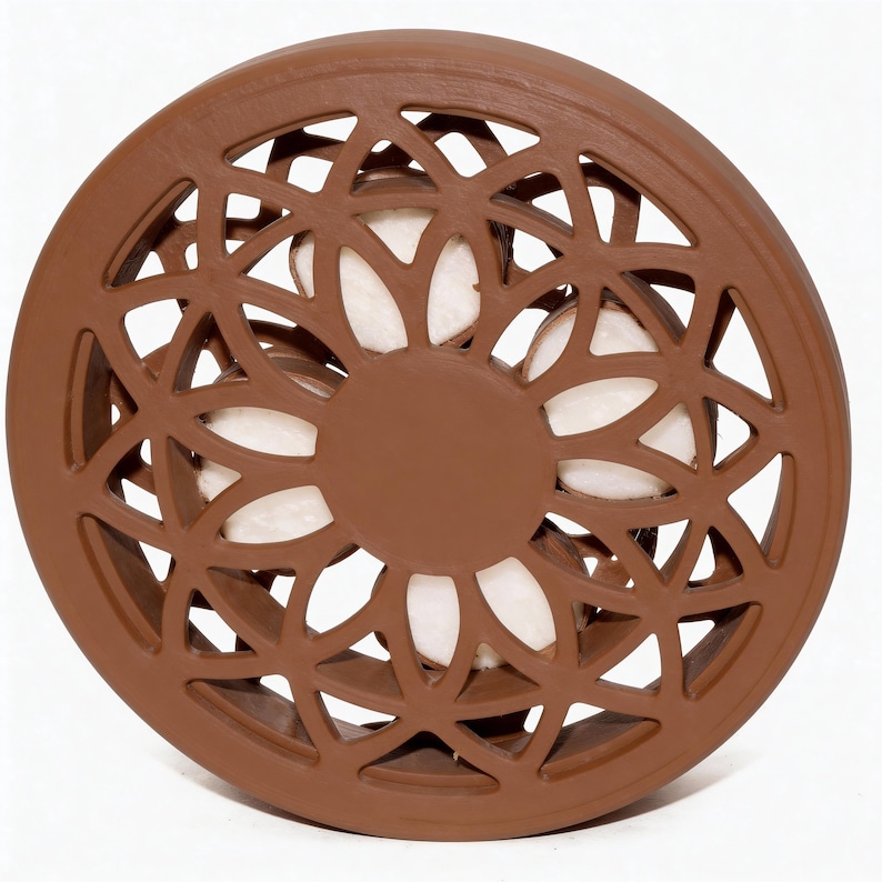 May include: A brown, circular decorative object with a floral, openwork design. The center features a solid brown circle, and the openwork reveals a white interior. The object is likely made of ceramic or a similar material.