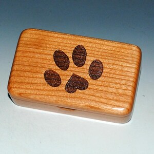 Small handmade in the USA natural cherry wood box with an engraved paw print with a heart about the size of a business card. Sanded to perfection and finished with many coats of tung oil. Interior is fully lined with blown in rayon fibers.