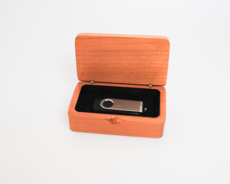 May include: A wooden box with a hinged lid, open to reveal a silver and black USB flash drive inside.