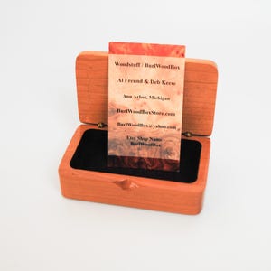 May include: A wooden box with a black velvet interior, open to reveal a business card with the text "Woodstuff/ Burl Wood Box", "Al Freund & Deb Keese", "Ann Arbor, Michigan", "BurlWoodBoxStore.com", "Burl WoodBox yahoo.com", "Etsy Shop Name", "BurlWood Box".