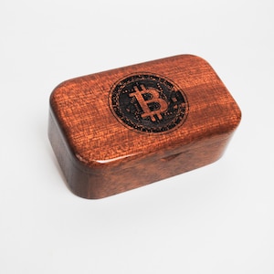 May include: A wooden box with a dark brown finish and a black Bitcoin logo on the top.