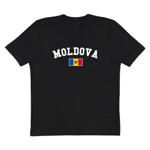 May include: Black t-shirt featuring the word "MOLDOVA" in white, arched lettering. Beneath the text is a small rectangular graphic of the Moldovan flag. The shirt has a crew neck and short sleeves.