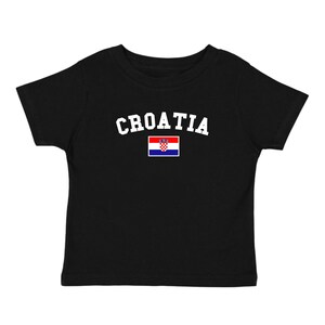 May include: Black t-shirt with the word "CROATIA" in white arched lettering above a small Croatian flag. The flag features a red, white, and blue design with a coat of arms.