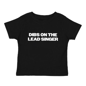 May include: Black toddler t-shirt featuring the text "DIBS ON THE LEAD SINGER" in bold white capital letters. The t-shirt is plain black and has short sleeves.