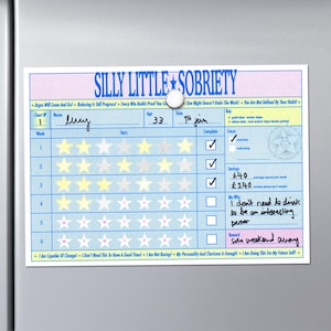 Può includere: Un grafico di sobrietà blu e bianco intitolato "Silly Little Sobriety" con un bottone magnetico. Il grafico include sezioni per monitorare i progressi, con valutazioni a stelle e caselle di controllo. Sono incluse frasi motivazionali.