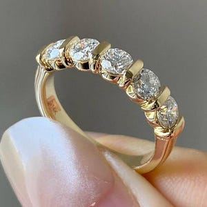 May include: A gold band with five round diamonds set in a prong setting.
