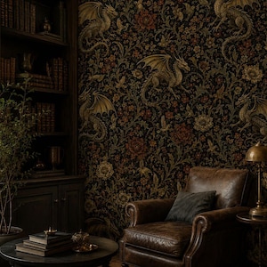 May include: A dark room featuring wallpaper with a repeating pattern of gold dragons, flowers, and foliage. A brown leather armchair with a dark cushion sits beside a small table with a brass lamp. A bookshelf and a potted plant are also present.