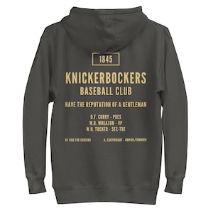 May include: A dark gray hooded sweatshirt with the text "1845 KNICKERBOCKERS BASEBALL CLUB HAVE THE REPUTATION OF A GENTLEMAN D.F. CURRY - PRES W.R. WHEATON - VP W.H. TUCKER - SEC-TRE 6C FINE FOR CURSING A. CARTWRIGHT - UMPIRE/FOUNDER" printed in yellow on the back.