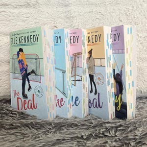 May include: A collection of five paperback books from the Off-Campus series by Elle Kennedy, featuring colorful illustrated covers with hockey themes, including titles like The Deal, and numerous small adhesive page markers attached to the edges.