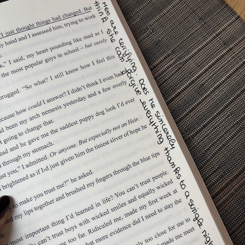 Puede incluir: P&aacute;ginas de un libro abierto con texto impreso y notas manuscritas en tinta negra en el borde derecho. Las notas incluyen frases como "Men are terrifying" y "forgive everything."
