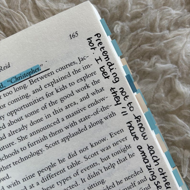 May include: Open book page with text and highlighted words. The page number 165 is visible. The text includes the words "Christopher" and "Pretending not to know each other". The book has blue and white page markers.
