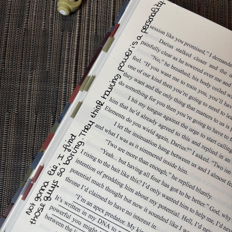 Puede incluir: Libro abierto con texto y marcadores de p&aacute;gina coloridos. El texto manuscrito en la p&aacute;gina dice: "Not gonna lie, I find those guys so boring. They think having power is a personality."