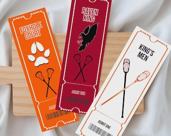 Könnte beinhalten: Drei farbenfrohe Event-Tickets mit einzigartigen Designs. Das orangefarbene Ticket trägt die Aufschrift "FOXHOLE COURT" mit Pfotenabdrücken und gekreuzten Lacrosse-Schlägern. Das weinrote Ticket trägt die Aufschrift "RAVEN KING" mit einem Raben und gekreuzten Schlägern. Das weiße Ticket trägt die Aufschrift "KING'S MEN" mit Lacrosse-Schlägern.