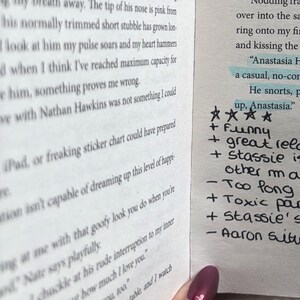 May include: A book page with printed black text and a handwritten review in the margin. The review includes four stars, plus signs for positive points like funny and great, and minus signs for negative points like too long and toxic.