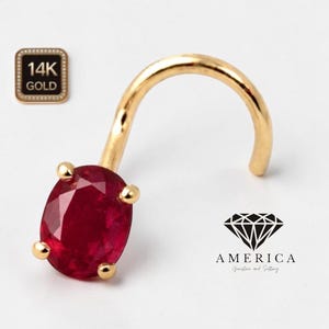 May include: A gold nose ring with a vibrant red oval-cut gemstone. The ring is curved and features a 14K gold stamp. The image also includes the text "AMERICA Gemstone and Setting".