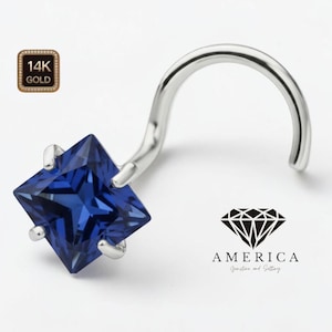 May include: A nose ring featuring a square, deep blue gemstone set in a silver-colored metal. The jewelry is curved and has a post for insertion. The image includes a logo that says "AMERICA Gemstone and Setting" and a "14K GOLD" stamp.
