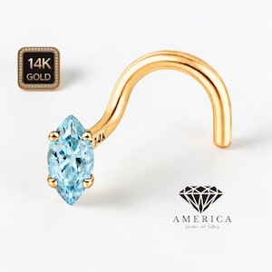 May include: A 14K gold nose stud with a marquise-cut, light blue gemstone. The curved stud features a polished finish and is set with small gold prongs. A small square emblem with "14K GOLD" is visible.