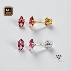 May include: Two pairs of stud earrings with pink marquise-cut gemstones. One pair features gold posts and settings, while the other has silver posts. The earrings are marked with "14K" and are set against a white background.