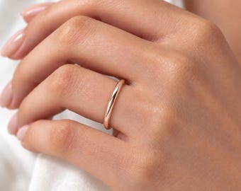 Puede incluir: Un anillo de banda en oro rosa pulido con una superficie lisa y redondeada. El anillo presenta una construcción de metal sólido simple con un acabado de alto brillo que refleja la luz uniformemente sobre su exterior curvo, de diseño limpio.