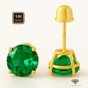 May include: A pair of gold earrings with round, faceted emerald green gemstones. The earrings are set in a gold bezel setting with a post and butterfly backing. The image also includes a gold 14K gold stamp.