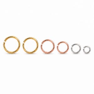 Puede incluir: Un conjunto de seis anillas de salto circulares dispuestas en una fila horizontal, disminuyendo de tamaño de izquierda a derecha. Los dos primeros anillos son dorados, los dos siguientes son de oro rosa y los dos últimos son plateados.
