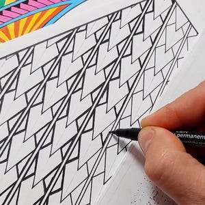 May include: A hand using a black permanent marker to draw geometric patterns on white paper. A colorful, abstract design is visible in the upper left corner. The image showcases the creation of intricate black and white artwork.