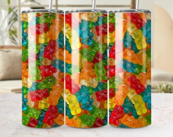 May include: Three stainless steel tumblers with a vibrant, colorful design of gummy bears. The gummy bears are in various colors, including red, orange, yellow, green, and blue. Each tumbler has a silver straw.