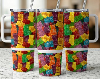 May include: Three stainless steel tumblers with white handles and lids. Each tumbler is covered in a colorful pattern of gummy bear candies. The tumblers have a white band near the bottom and include a silver straw.
