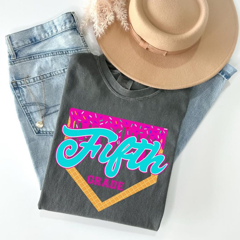 a gray t-shirt with a graphic design, a pair of jeans, and a beige hat, all laid out on a white background.