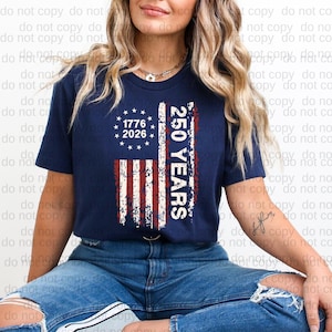 A woman wearing a navy blue t-shirt with a graphic design featuring the American flag and the text "1776 2026 250 YEARS" printed on it.