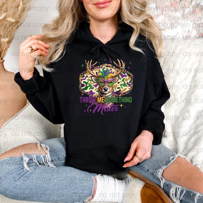 A woman wearing a black hoodie with a colorful graphic design and text printed on it.